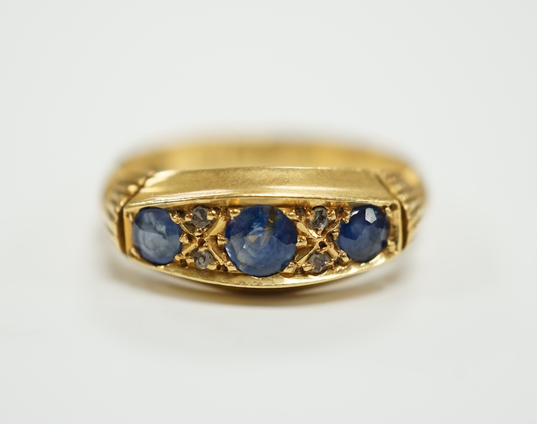 A George V 18ct gold and three stone sapphire set ring, with diamond chip spacers, size K, gross weight 3.3 grams.